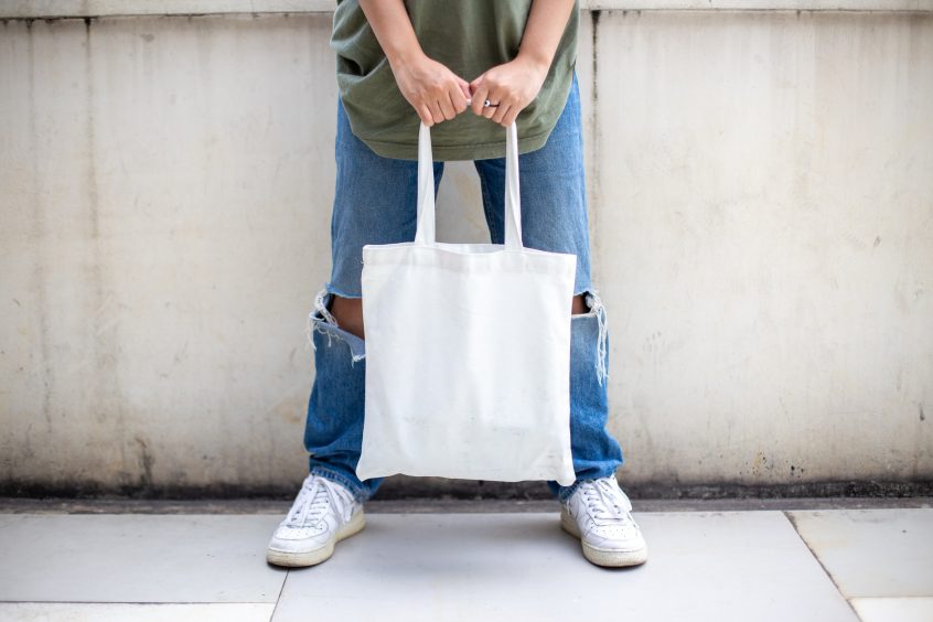 woman holding white tote bag